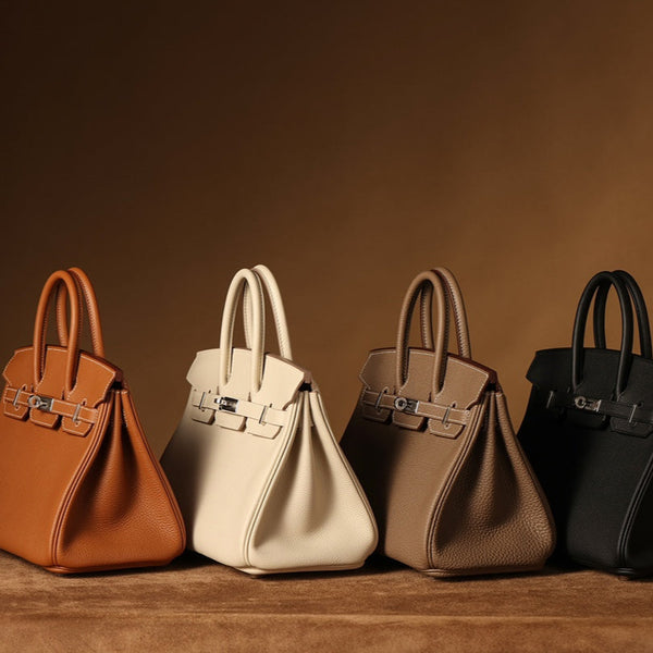 Four Hermès Birkin-style leather handbags in Gold, Craie, Etoupe, and Noir with palladium hardware, displayed on a warm brown studio background.