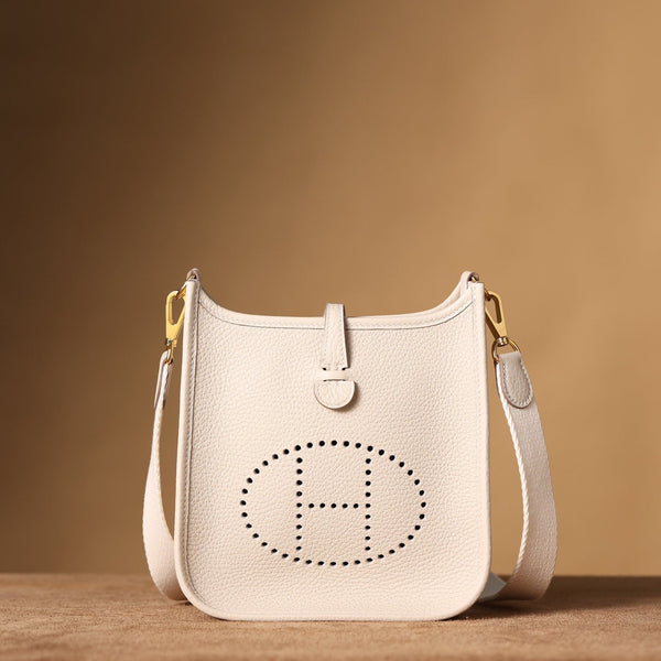 Front view of restored used Hermès Evelyne bag by Empyrean Atelier, in white Togo calfskin with perforated H logo and gold-tone hardware.