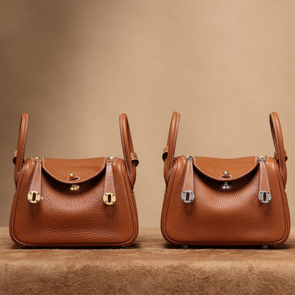 Front view of two restored used Hermès Mini Lindy bags, one with gold hardware and the other with palladium, by Empyrean Atelier.