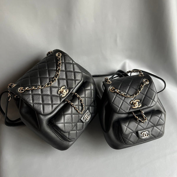  pre-owned Chanel Duma and mini Duma 22A backpacks in black caviar leather, restored by Empyrean Atelier. Shown in two sizes with gold-tone chain straps.
